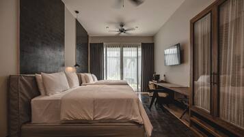 Una habitación de hotel moderna con una cama grande, un escritorio, un televisor y un ventilador de techo.
