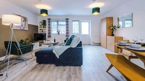 A modern living room with a sofa, a dining table set for two, and a television. - Spacious House, Incredible Location, FREE Parking! (Chester)