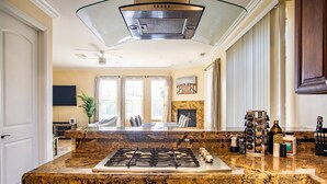 A kitchen with granite countertops, a gas stove, and a range hood.
