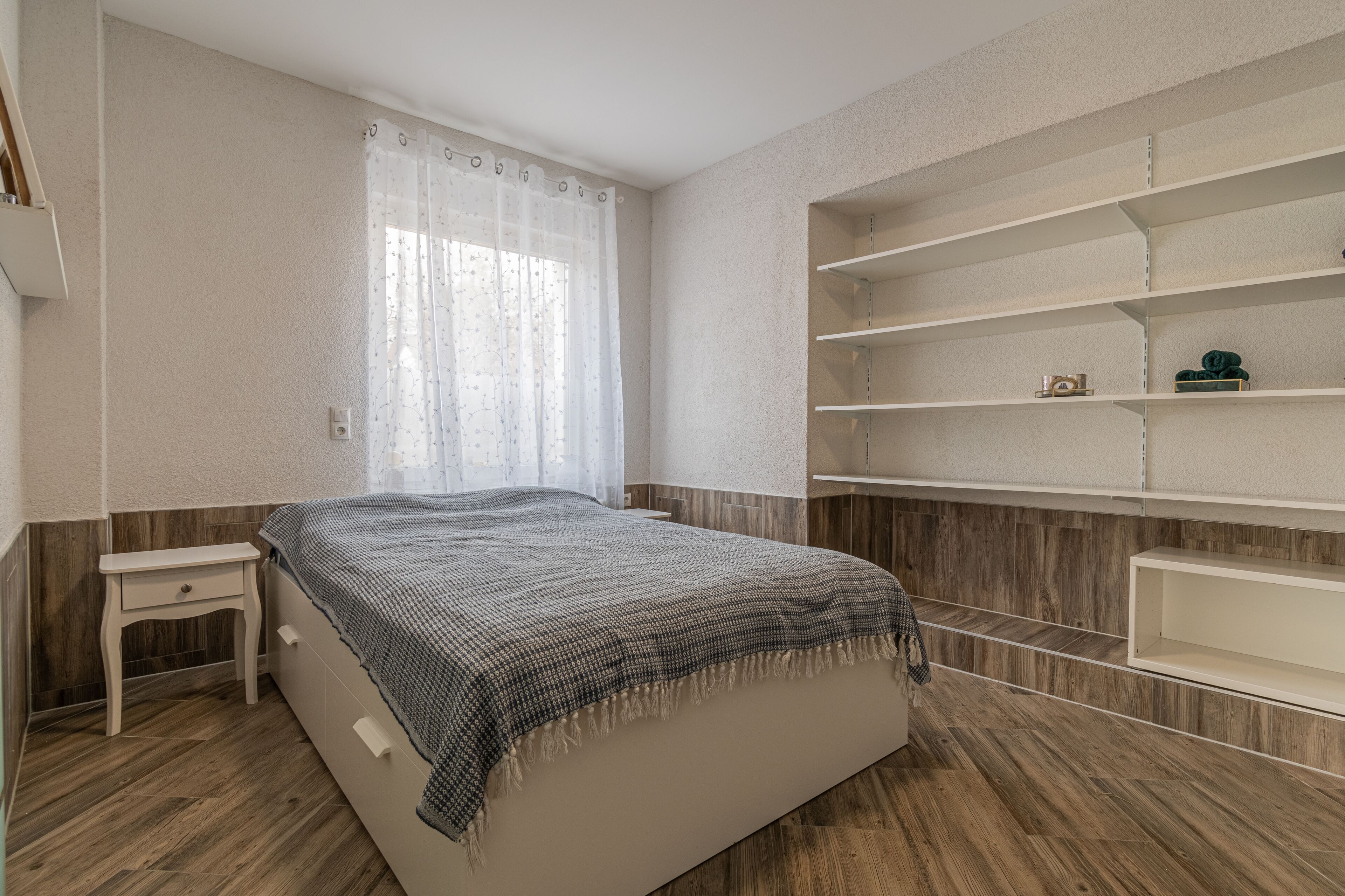 A bedroom with a bed, a nightstand, and built-in shelves.