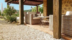 A covered outdoor seating area with wicker furniture and a bicycle. - Hill-top haven with private pool & endless views (Belvezet)