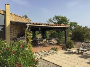 An outdoor patio area with a stone wall, a pergola, a barbecue grill, and a seating arrangement. - Hill-top haven with private pool & endless views (Belvezet)