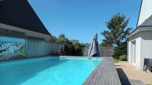 En swimmingpool med ett trädäck runt om, omgiven av ett staket och en väggmålning.