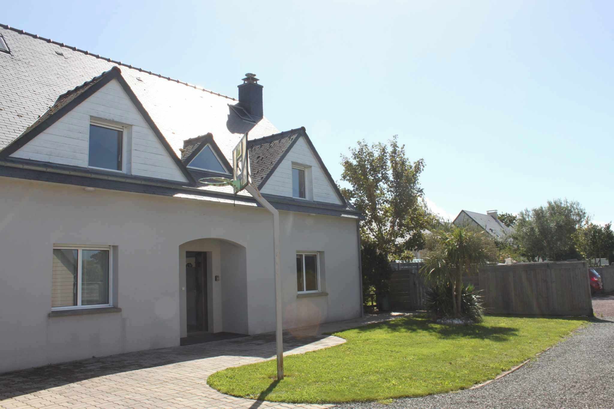 A residential house with a sloped roof, a front door, and a small front yard with a tree and a fence.