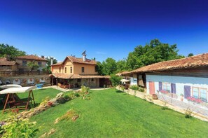 A courtyard with a grassy lawn, a small pool, and a building with a tiled roof.