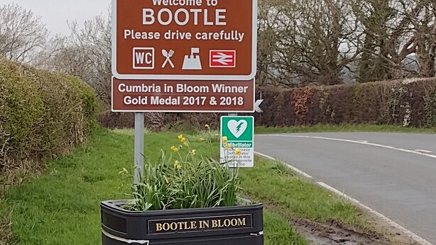 A welcome sign for Bootle, a Cumbria in Bloom winner, and a public access defibrillator sign. - Remarkable 3-bed House in Millom (Millom)