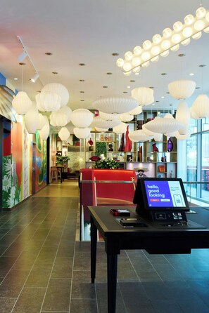 A hotel lobby with modern lighting fixtures, a reception desk, and a seating area.