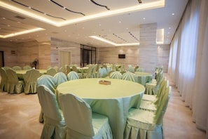 A banquet hall with round tables and chairs, a marble wall, and a modern ceiling design. - Lavande Hotel (Guilin Railway Station Mixc) (Guilin)