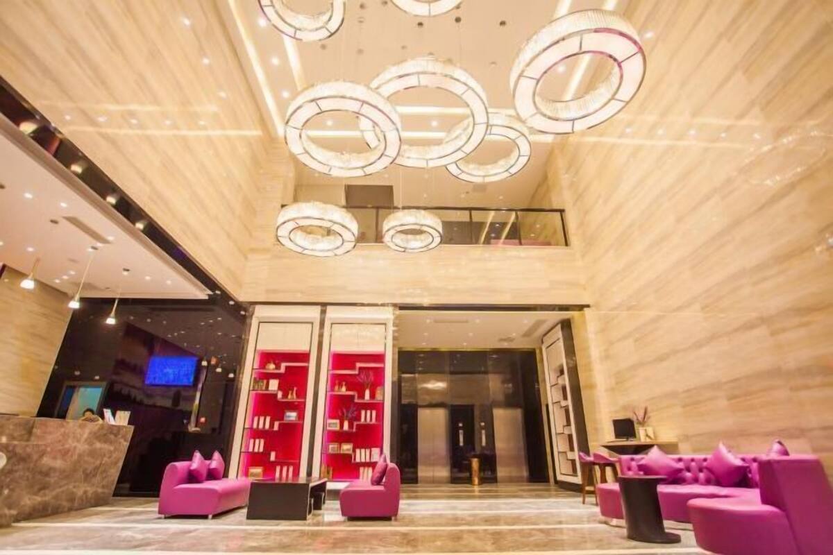 A modern lobby with a reception desk, seating area, and a staircase leading to an upper level.