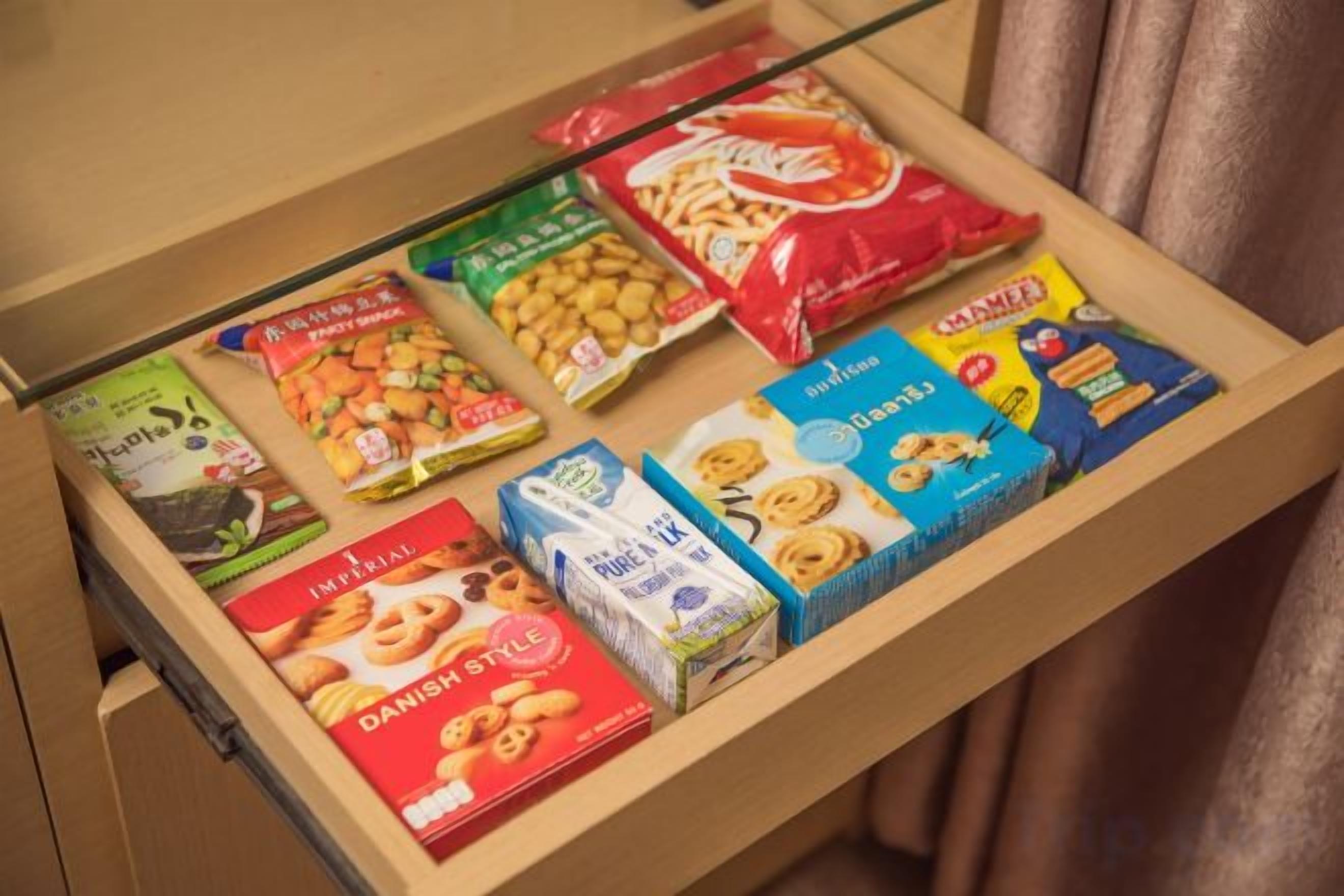 A drawer with various packaged food items including snacks and biscuits.