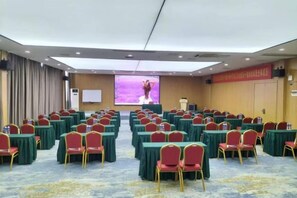 A conference room with rows of tables and chairs, a podium, and a large screen. - Lavande Hotel (Guilin Railway Station Mixc) (Guilin)