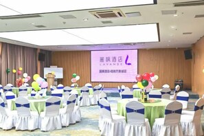 A conference room with rows of tables and chairs, a stage with a screen, and a banner. - Lavande Hotel (Guilin Railway Station Mixc) (Guilin)