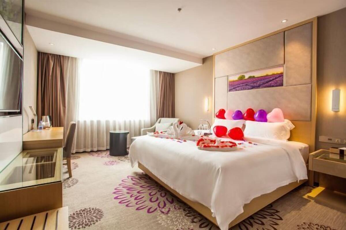 A hotel room with a bed, a desk, and a TV.