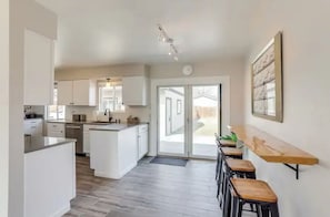 Una cocina moderna con armarios blancos, una isla central y un comedor con taburetes.