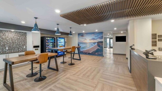A modern hotel lobby with a reception desk, seating area, and a large wall mural. - Extended Stay America Premier Suites - San Diego - San Marcos (San Marcos)