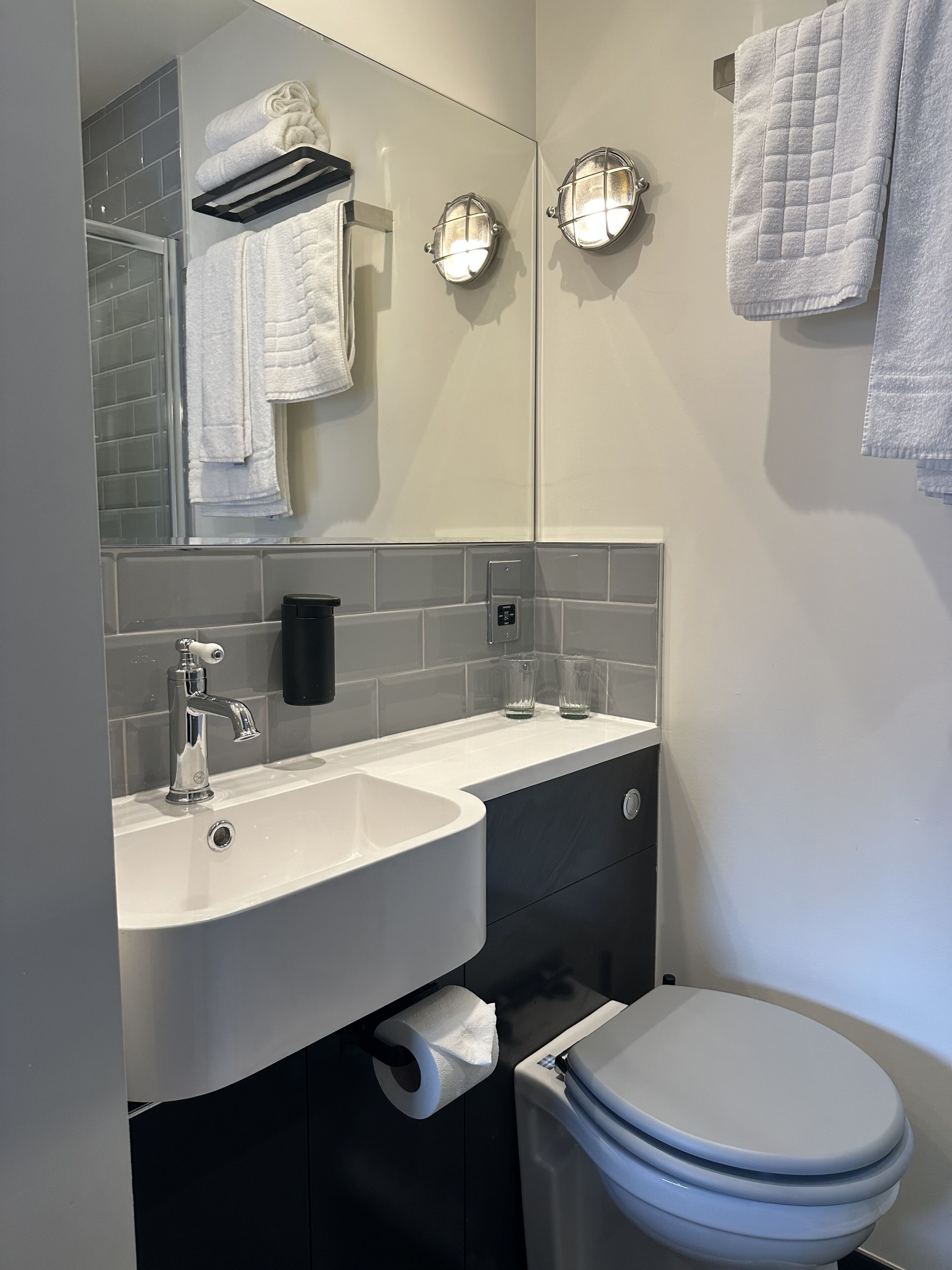 A modern bathroom with a white sink, a toilet, and a mirror above the sink.