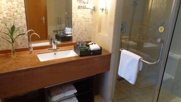 A bathroom with a wooden vanity, two sinks, a glass shower enclosure, and a towel rack.