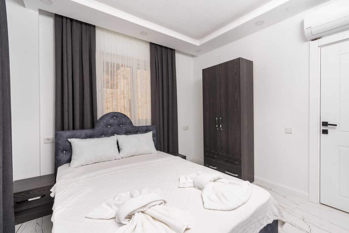 A hotel room with a bed, a wardrobe, a door, and an air conditioning unit.