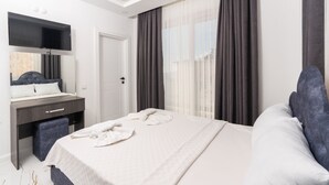 Une chambre d’hôtel moderne dotée d’un grand lit, d’un bureau avec une chaise, d’une télévision à écran plat et d’une grande fenêtre avec des rideaux.