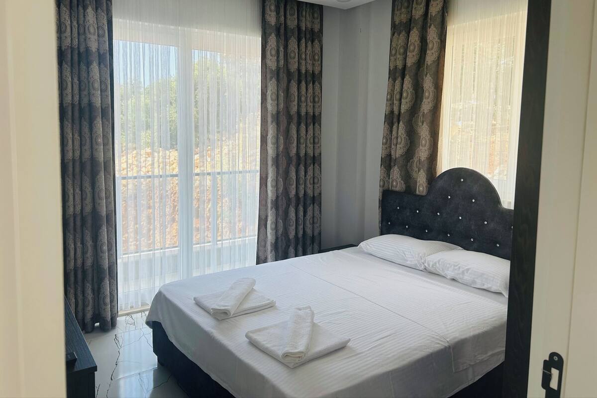 A hotel room with a bed, curtains, and a window.