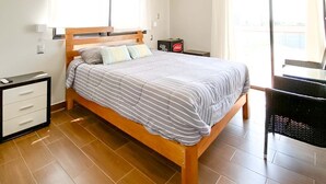A bedroom with a wooden bed, a nightstand, a chair, and a window with curtains. - Pisco Villa: Private Pool & Games on 1400m² (Pisco)