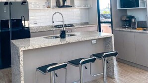 A modern kitchen with a central island, bar stools, and pendant lighting. - Pisco Villa: Private Pool & Games on 1400m² (Pisco)