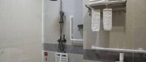 A modern bathroom with a shower, grab bars, a towel rack, and a toilet paper holder.
