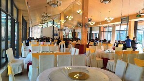 A banquet hall with round tables, white chairs, and chandeliers. - Mengshiyuan Hot Spring Resort (Anning)