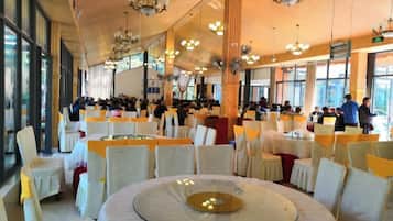 Un salón de banquetes con mesas redondas, sillas y candelabros.