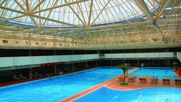 An indoor swimming pool with a high ceiling and a glass structure.