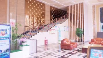 Un vestíbulo de hotel con una escalera, mostrador de recepción y zona de estar.