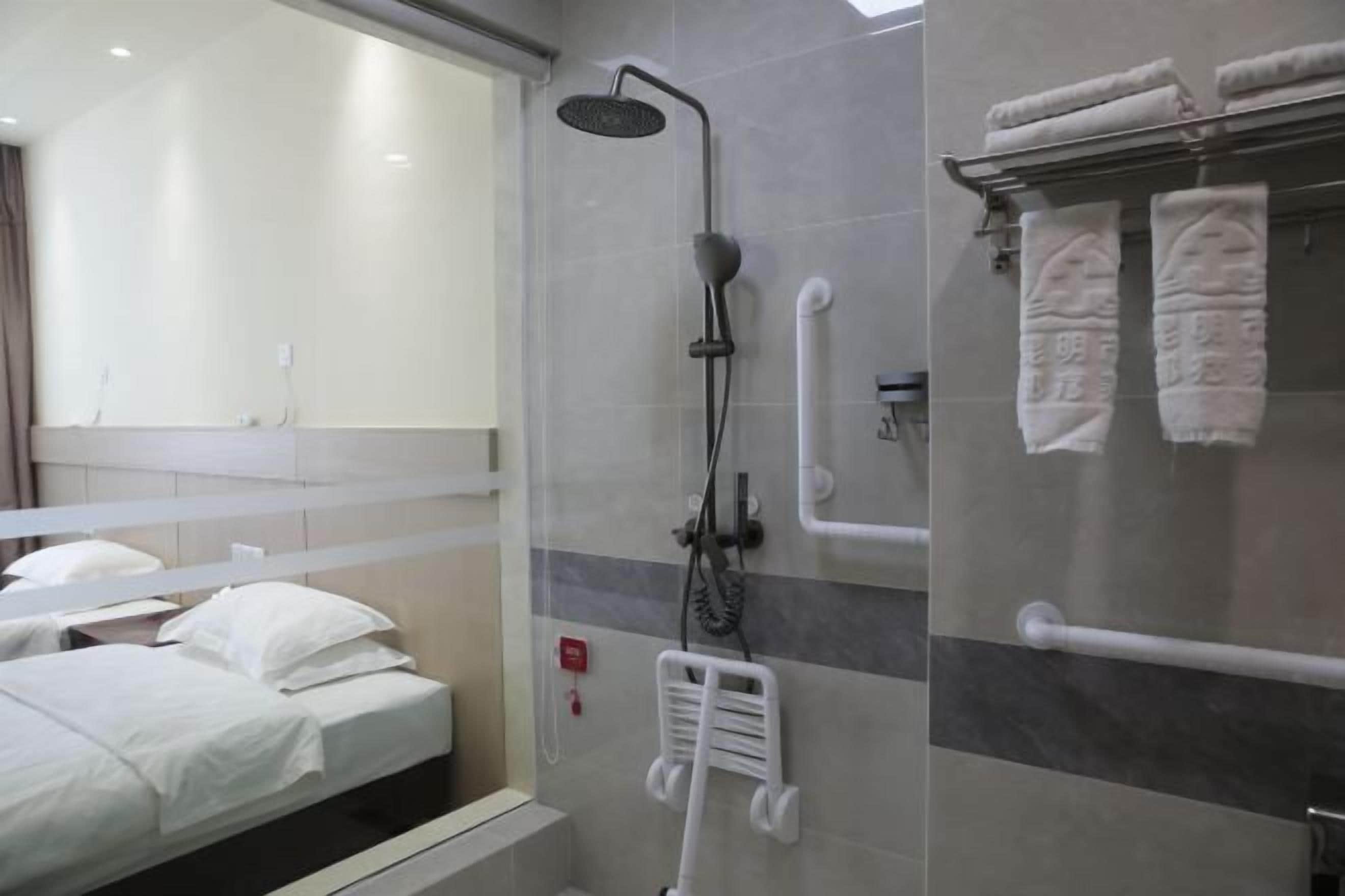 Casa de banho de hotel com chuveiro, porta-toalhas e secador de mãos.