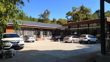 Un edificio con estacionamiento, varios autos y un cielo azul despejado.
