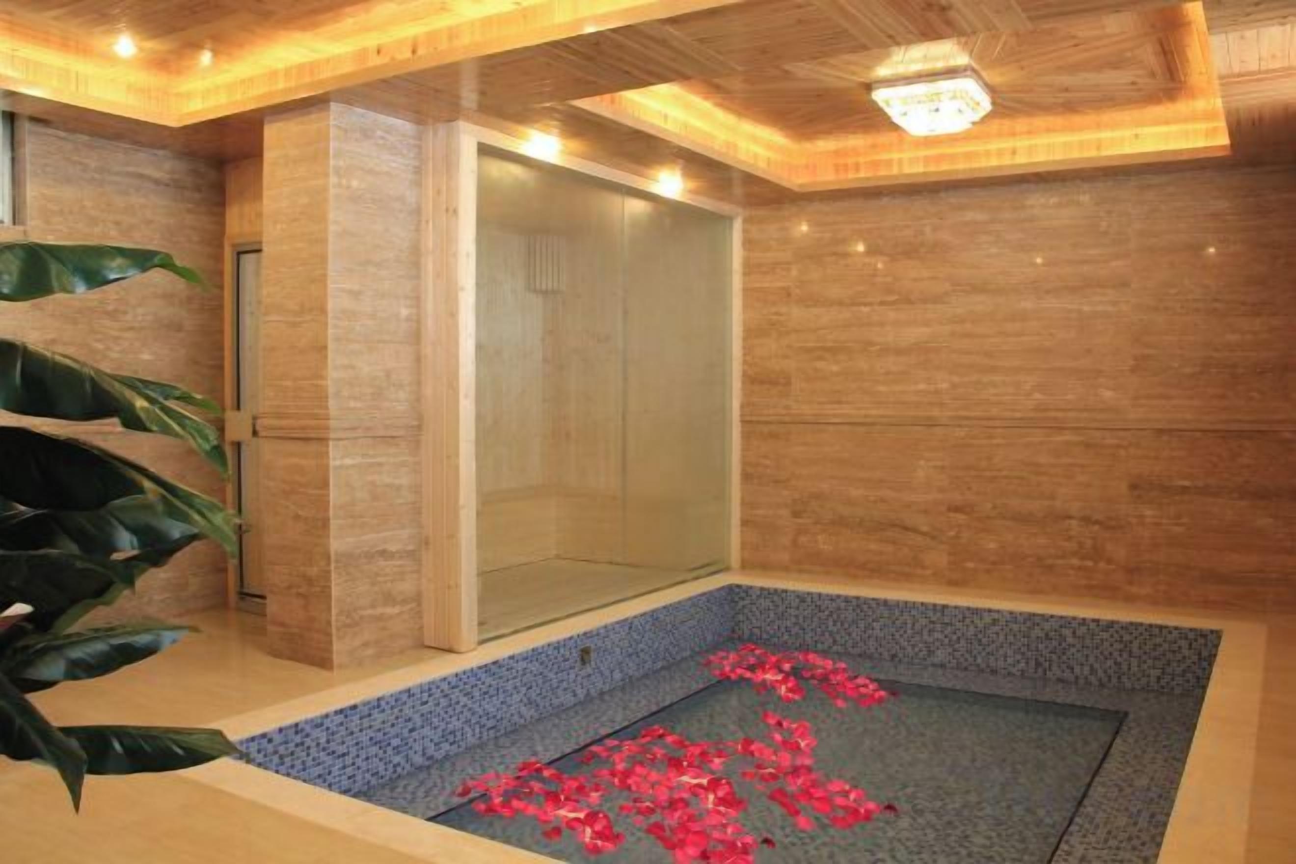A spa room with a glass enclosure, a tiled floor, and a potted plant.