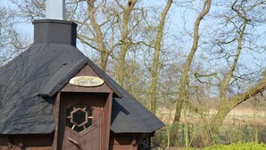 A wooden cabin with a sign reading "Grillhaus" and a hexagonal window.