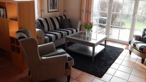 A living room with a sofa, armchairs, a coffee table, and a bookshelf.