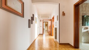 Ein Flur mit sechseckischem Musterfliesenbelag, gerahmten Kunstwerken an den Wänden und einer Holztür zu einem Badezimmer.
