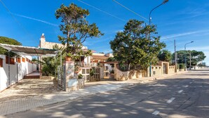 A street view with a row of houses, a paved sidewalk, and a clear blue sky.