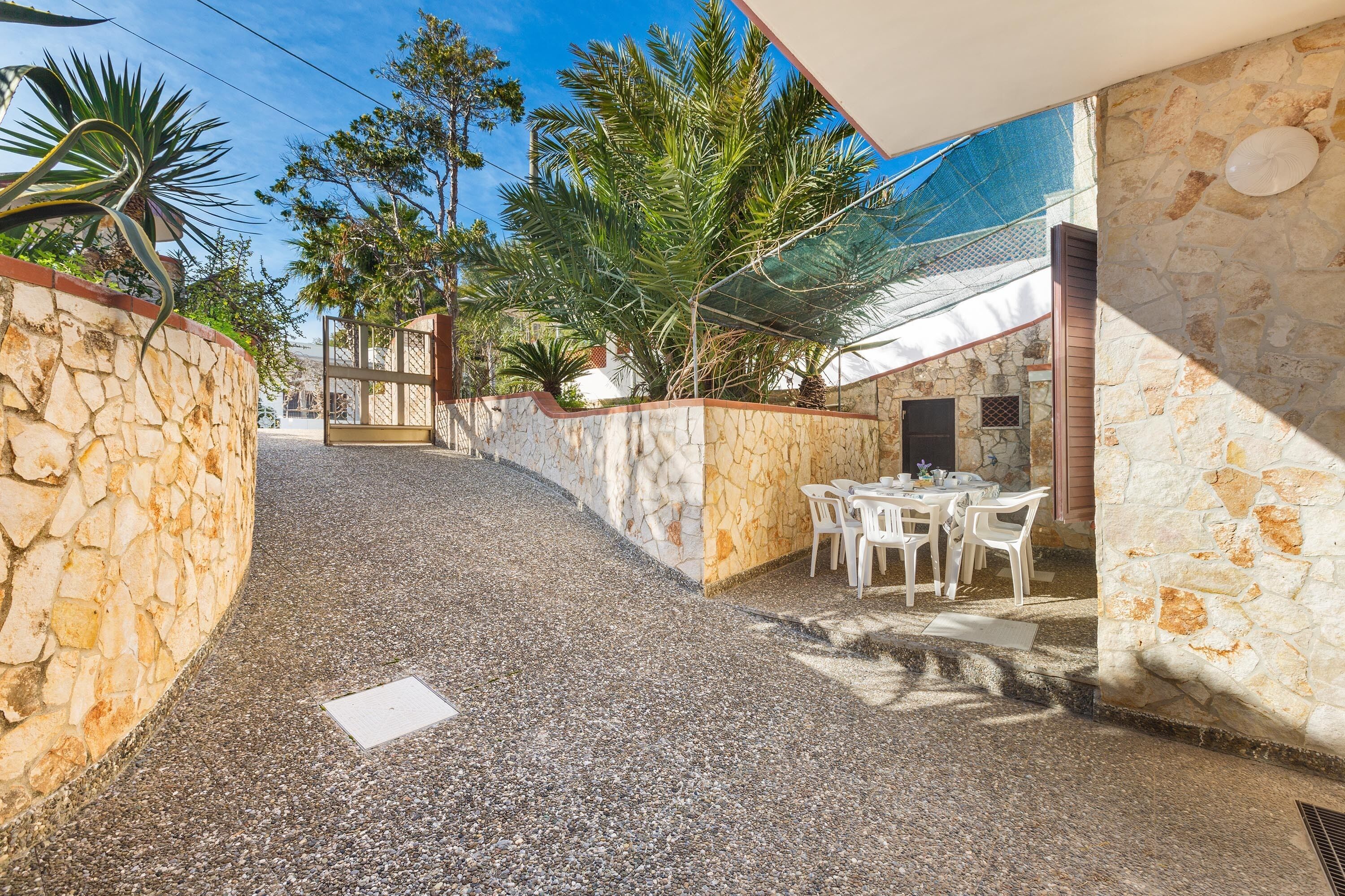 A patio area with stone walls, a gravel path, and outdoor seating.