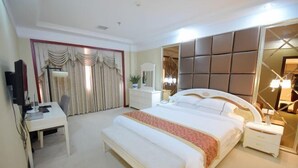 A hotel room with a large bed, a desk, a chair, a bedside table, and a mirror. - Censhan Hotel (Hengfeng)