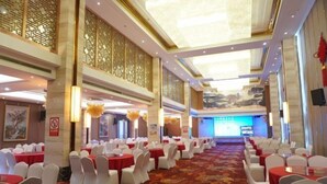 A banquet hall with round tables, white chairs, and red tablecloths. - Censhan Hotel (Hengfeng)