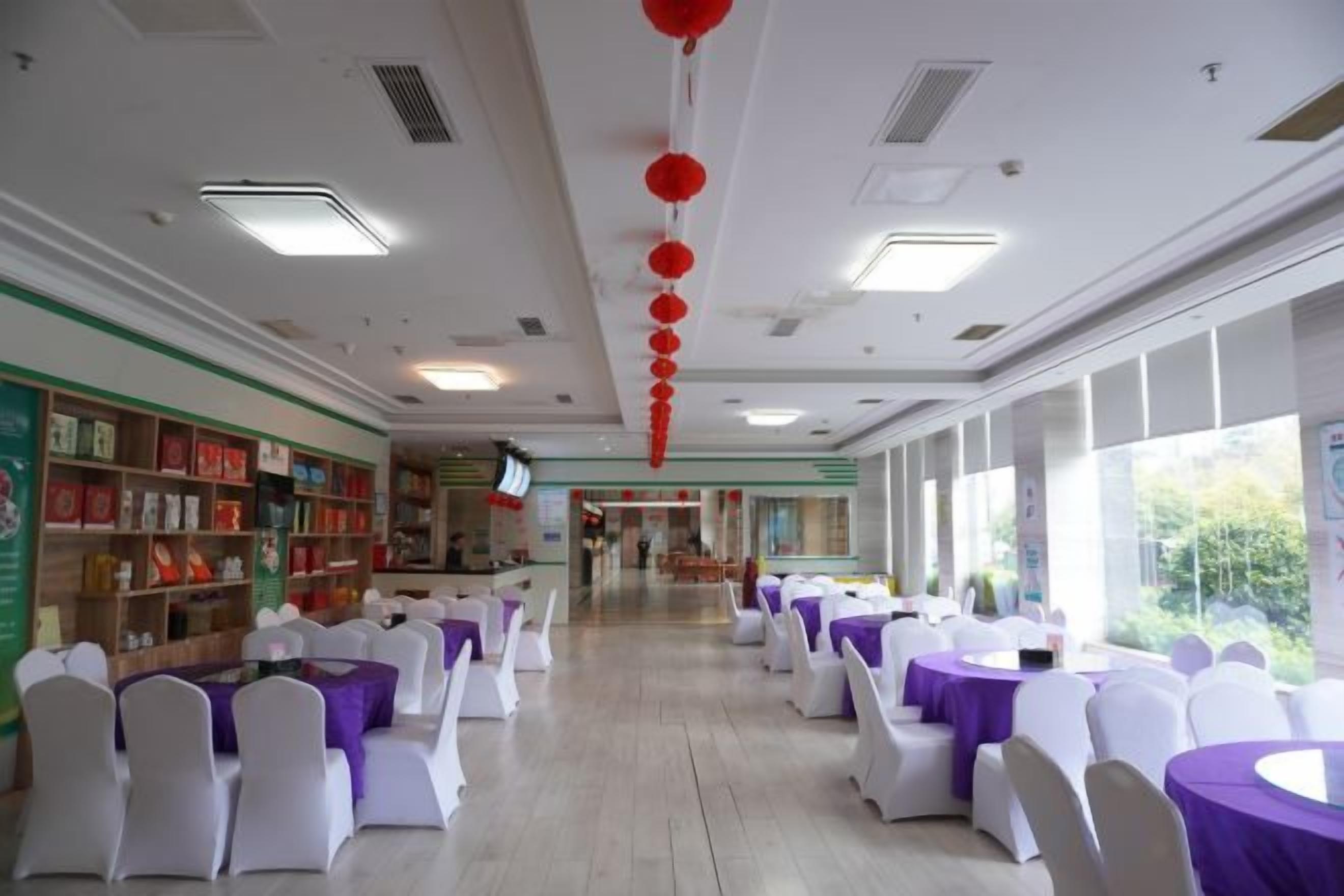 A spacious hall with rows of tables and chairs, a long corridor, and large windows.