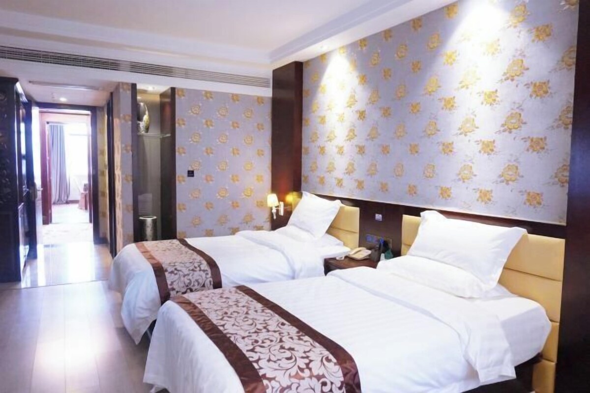 Habitación de hotel con dos camas, un espejo grande y un papel tapiz estampado.