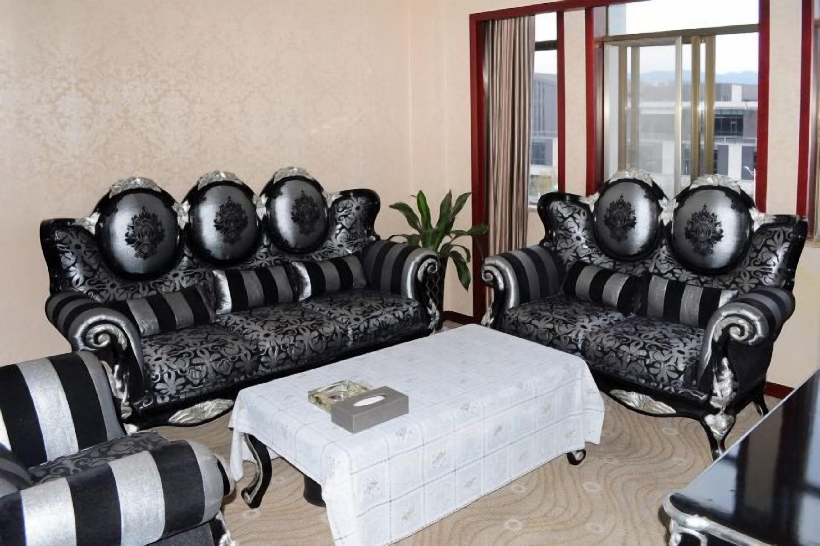 Una habitación con dos sofás de estampado blanco y negro, una mesa de centro blanca y una planta en maceta.