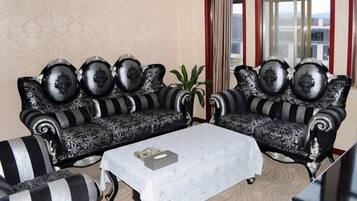 Una habitación con dos sofás de estampado blanco y negro, una mesa de centro blanca y una planta en maceta.