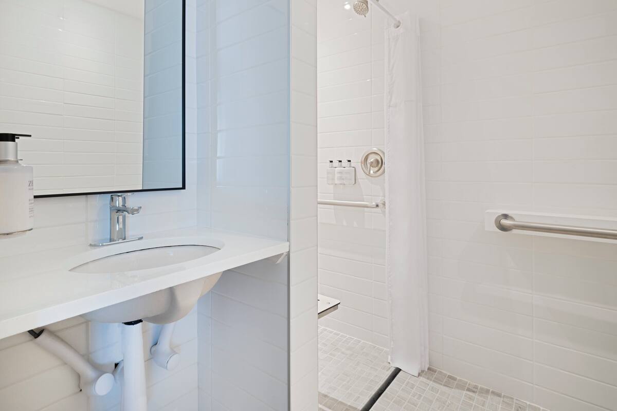 Een moderne badkamer met een witte wastafel, spiegel en douchegedeelte.