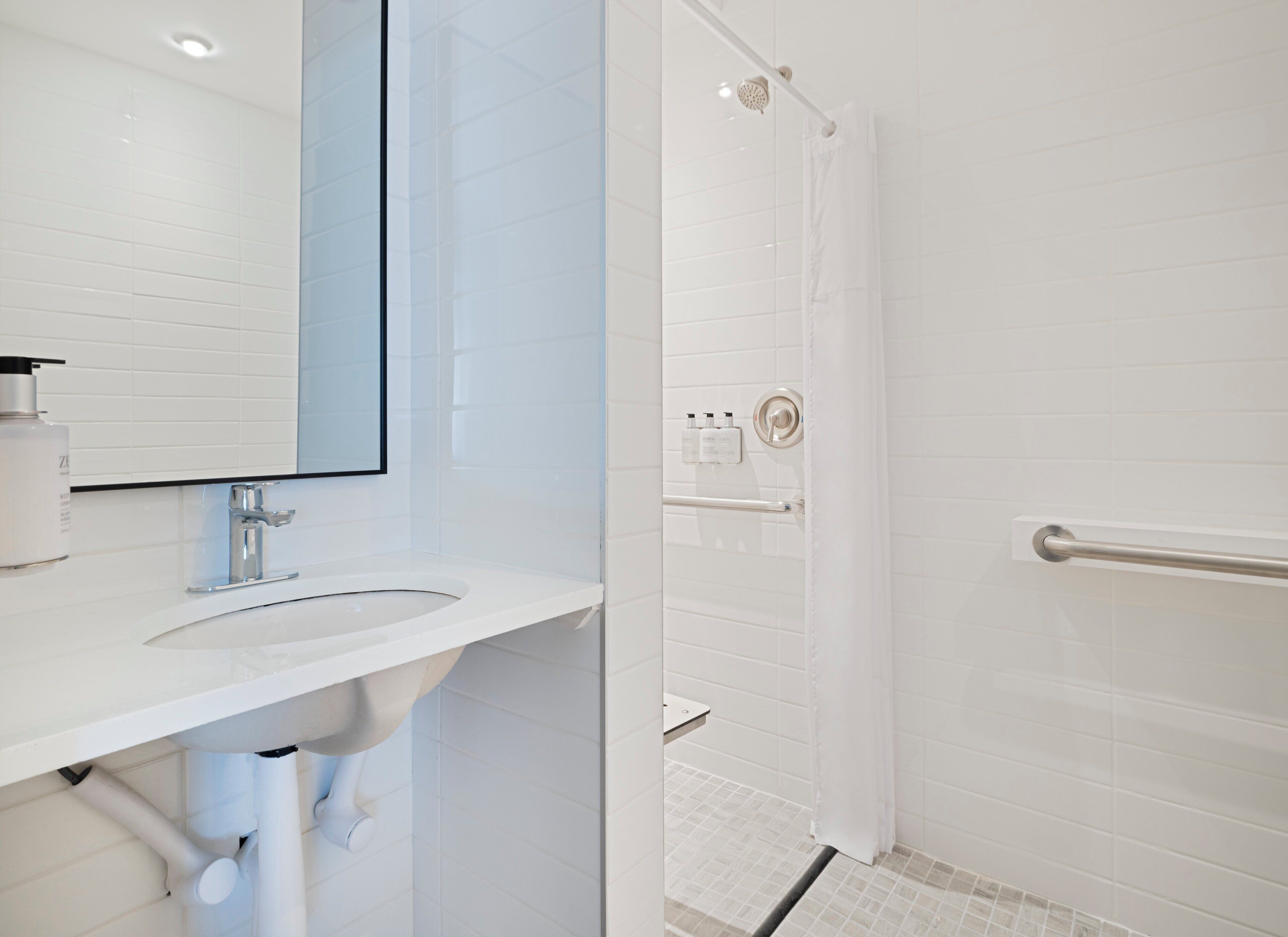 A modern bathroom with a white sink, mirror, and shower area.