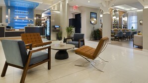 Un hall d’hôtel moderne comprenant un comptoir d’accueil, un espace salon et un espace repas.