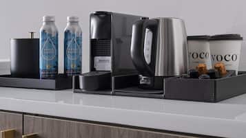 Een koffiehoek met een koffiezetapparaat, waterflessen en een koffiekan op een aanrecht.