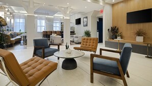 Un hall d’entrée spacieux avec une table basse ronde, plusieurs coins salon et un comptoir d’accueil.